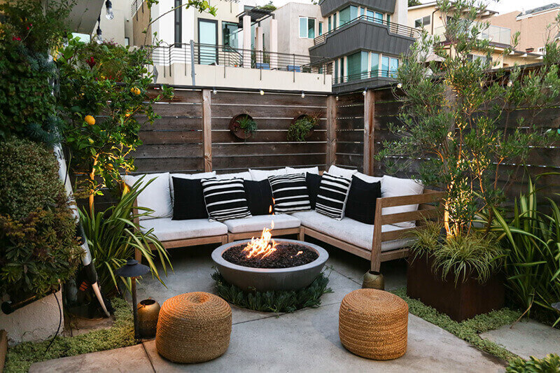 small outdoor gated patio with couches and a fireplace