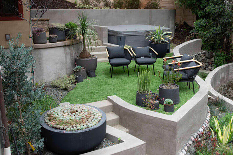 unusual layout hillside backyard area with chairs, potted plants and a firepit