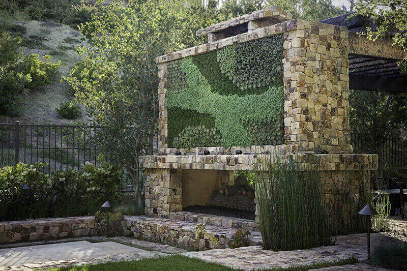 a large outdoor fireplace with a livinng wall - a mosaic of different plant leaves on the front